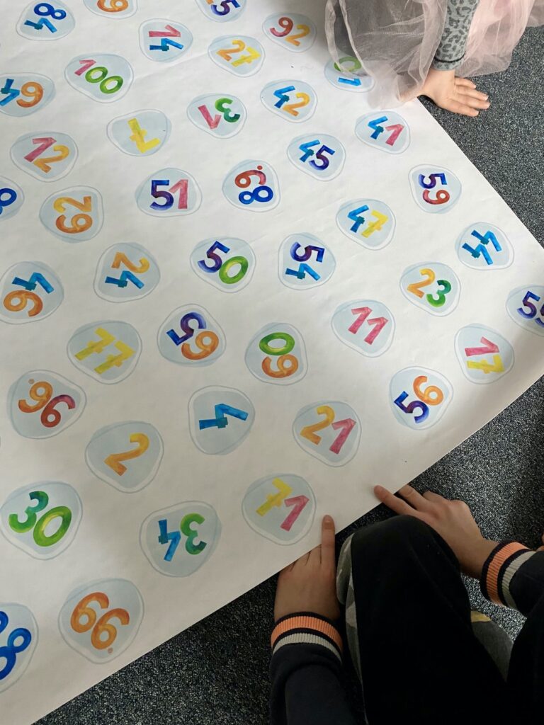 Dzieci uczą się liczb po angielsku na dużej macie z cyframi